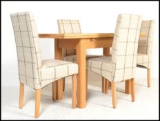 A contemporary oak extending dining table being raised on squared legs with fold over extending full