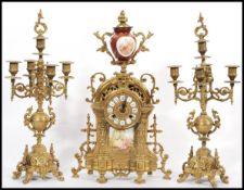 A vintage 20th century German gilt brass mantel clock and garniture set. The clock with red