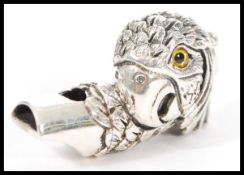 A stamped sterling silver whistle in the form of a parrot having yellow and black glass eyes and a
