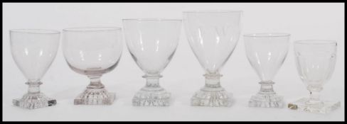 A group of five 19th century Georgian glass drinking glasses rummers raised on square bases with
