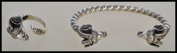 A stamped 925 silver bangle of twisted form having two rams head finials along with a rams head