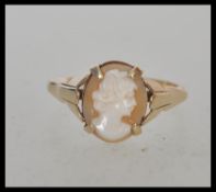 A stamped 9ct gold cameo ring set with an oval cameo head facing right with decorative shoulders.