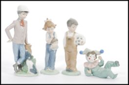 A group of four Lladro type Nao figurines to include reclined clown child, boy with ball, boy at