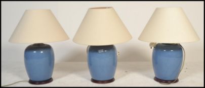 A set of 3 contemporary large ceramic blue glaze bulbous table lamps - lights. Each raised on wooden