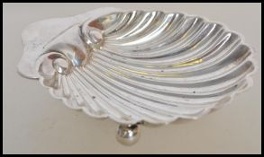 An early 20th century silver hallmarked scallop dish raised on bun feet with shaped handle.