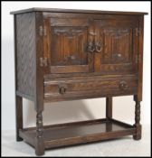 An Old Charm / Jaycee style oak hall cupboard having carved linen fold decoration being raised on