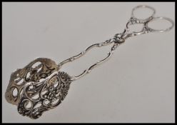 A continental silver 830S stamped pair of dessert sugar tongs having foliage and scrollwork