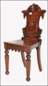 A Victorian 19th century solid mahogany armorial hall chair. The unusual shaped back with a