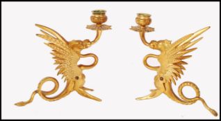 A pair of 19th century gilt brass candlesticks being in the form of Griffin's having single candle