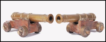 A pair of good early 20th century desk top brass and oak cannons. The detailed miniature brass canon