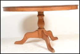 A 20th Century pine dining table having a circular top raised on a central turned column above three