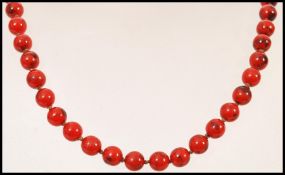 A vintage early 20th century red hardstone bead necklace having a gold claw clasp.
