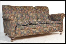 A 1920's Chesterfield 3 seat sofa settee being raised on bun feet with castors having barrel arms