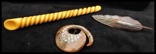A early 20th century carved horn brooch in the shape of a leaf, together with a large bakelite