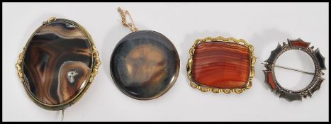 A collection of four 19th Century polished stone brooches set within silver white metal mounts.