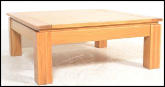 A contemporary large oak coffee - occasional table of square form being raised on well turned legs