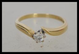 A hallmarked 18ct gold and solitaire crossover diamond ring, prong set with a brilliant cut diamond.