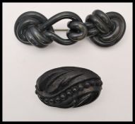 A circa 19th century Victorian vulcanite brooch together with a carved jet brooch. Largest