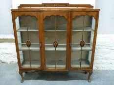 An Edwardian inlaid mahogany glazed breakfront cabinet raised on cabriole legs,
