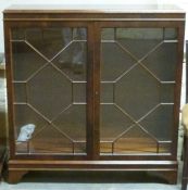 An astragal glazed walnut veneered bookcase/display cabinet with two shelves and lockable doors,