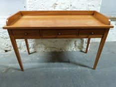 A galleried three drawer table raised on tapering legs,