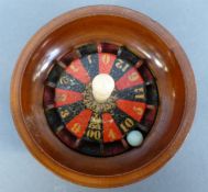 A 19thC turned treen surprise roulette wheel with revolving wheel and entry hole for the ball, H6cm,