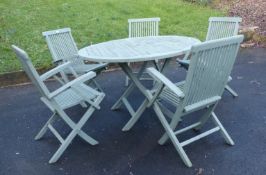 A circular teak garden table and five chairs and green parasol,