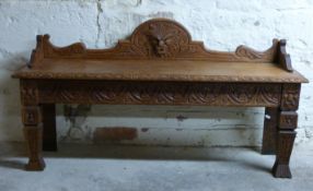 A carved oak hall or window seat with lion mask pediment and legs,
