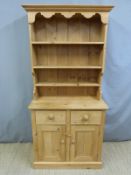 A small pine dresser with plate rack above and two drawers and cupboards below,