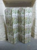 A four fold screen with printed flower fabric decoration and panelled tapestry North African scenes