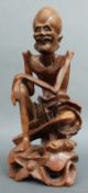 A carved wooden Chinese figure of an emaciated immortal with bone teeth,
