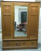 An Art Nouveau inlaid oak wardrobe with bevelled mirror door and two drawers,