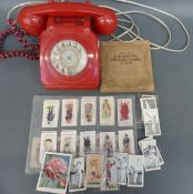 A vintage red telephone and various cigarette cards