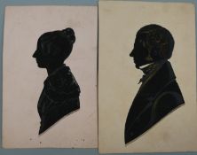 A pair of Victorian silhouettes of male and female figures with silver and gold highlights,