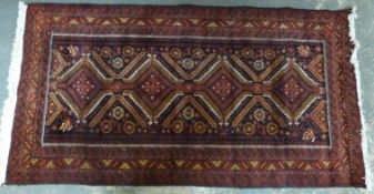 A Persian wool rug with geometric borders on a wine ground,