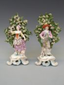 A pair of 19thC Staffordshire figures, shepherd and shepherdess against a bocage setting,