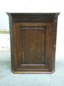 An 18thC oak corner cupboard the pedestal top with panelled door and three shelves to painted
