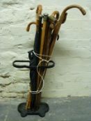 A cast iron stick stand with sticks and umbrella including silver topped, malacca cane,
