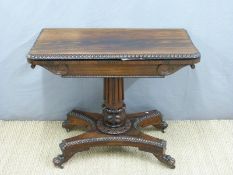 A 19thC rosewood fold over card table supported by a ridged circular column quatrefoil base,