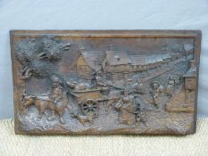A 19thC carved oak panel of a village scene with pig in cart, the figures in Dutch style costume,
