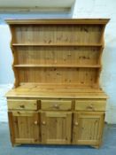 A pine dresser having three drawers and three cupboards with plate rack above,