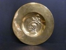 A brass charger on wooden stand