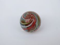 A very large handmade glass marble with red, yellow,