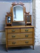 A satinwood Art Nouveau dressing table with triple bevelled mirror and brass stylised handles,