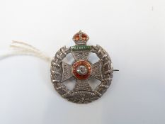 A silver badge marked sterling, reading 'Waterloo' in a green enamel tablet,