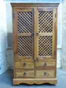 A modern hardwood cupboard with lattice fronted doors and four drawers below,