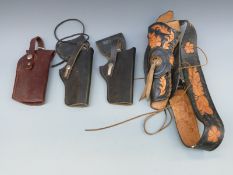 Four leather pistol holsters one mounted on a belt with engraved and embossed decoration of flowers.