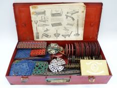 A collection of various Meccano parts including gears and wheels in metal carry case