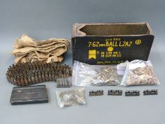A large collection of spent brass ammunition of various calibres in a metal ammunition box.