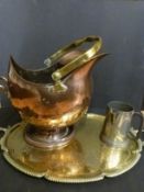 A beaten copper helmet style coal scuttle together with an embossed brass serving tray,